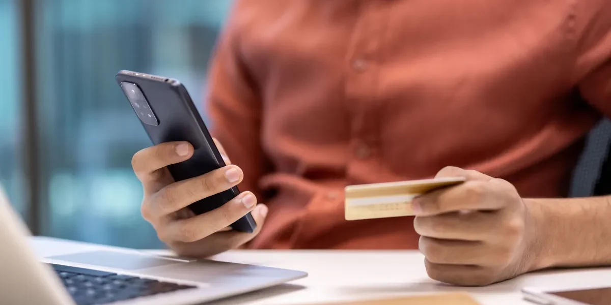 Bankkártyát és okostelefont tartó kéz