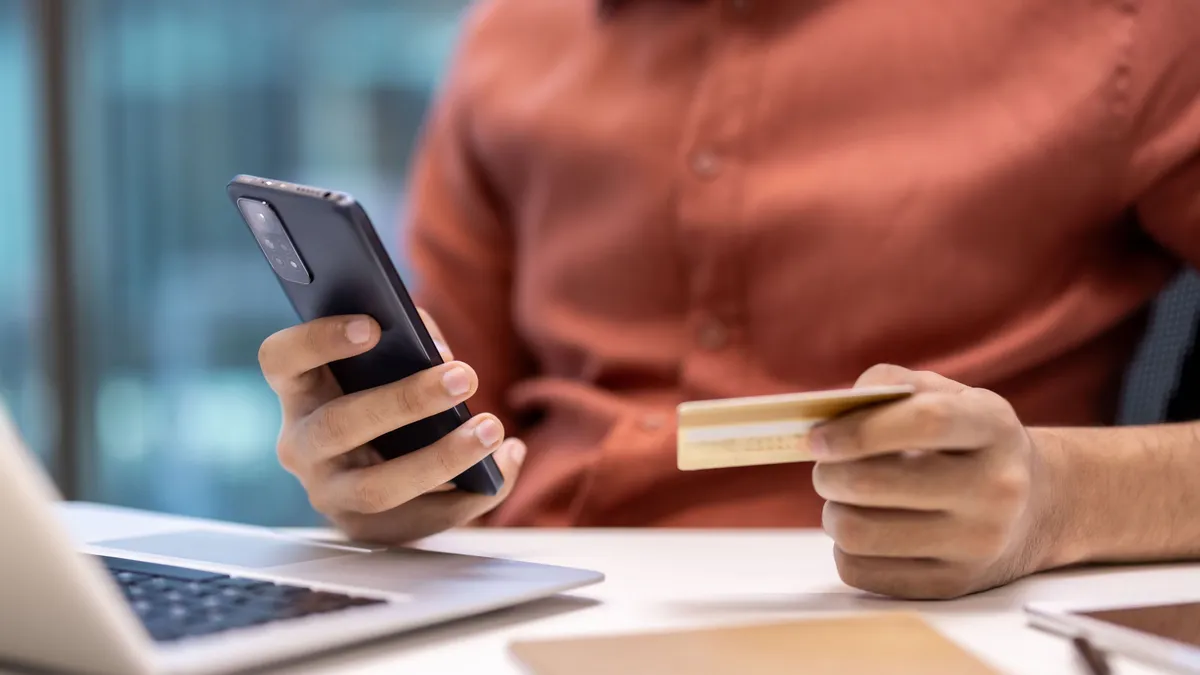 Bankkártyát és okostelefont tartó kéz